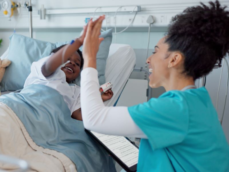 Eine Krankenschwester und ein Kind als Patient geben sich ein fröhliches High-Five