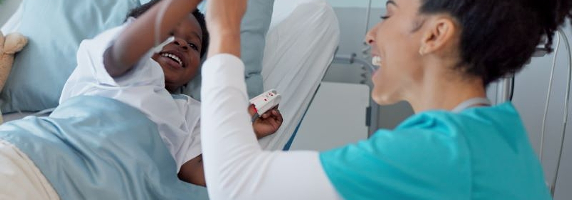 A nurse and a child patient share a cheerful high five