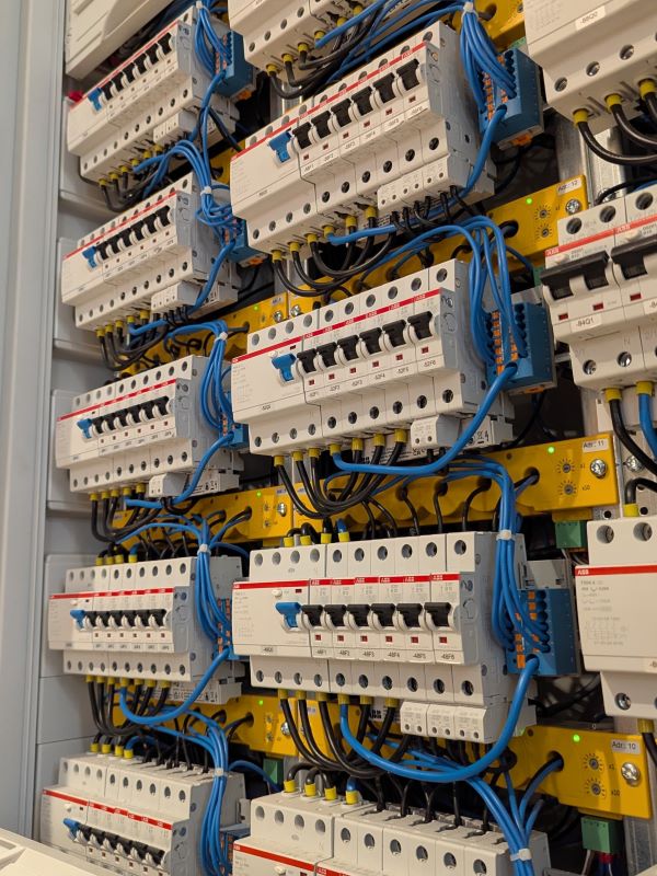 Blick in einen Schaltschrank mit grauen Leistungsschutzschaltern und gelben Bender Differenzstrom-Überwachungsgeräten RCMS150